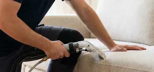 Professional upholstery cleaner deep-cleaning a fabric sofa with a handheld extraction tool, Baltimore, MD.